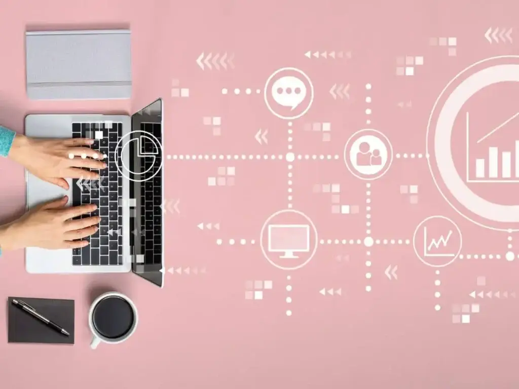 a woman is using a laptop on a pink background.