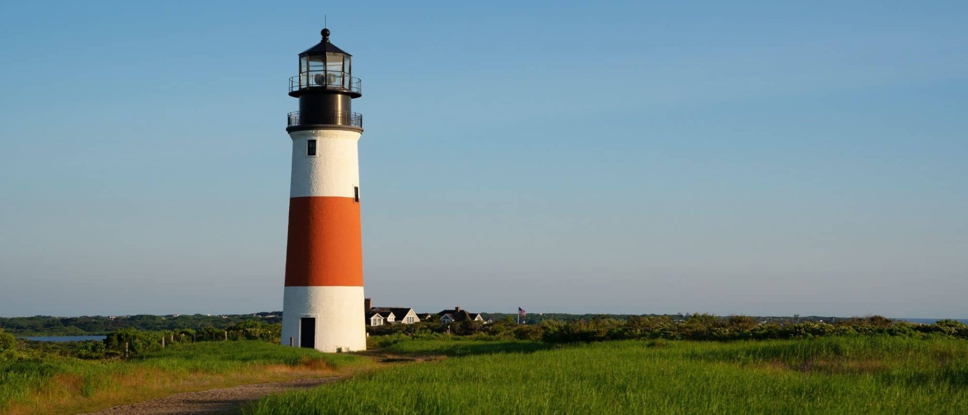 A lighthouse sits on top of a grassy hill.