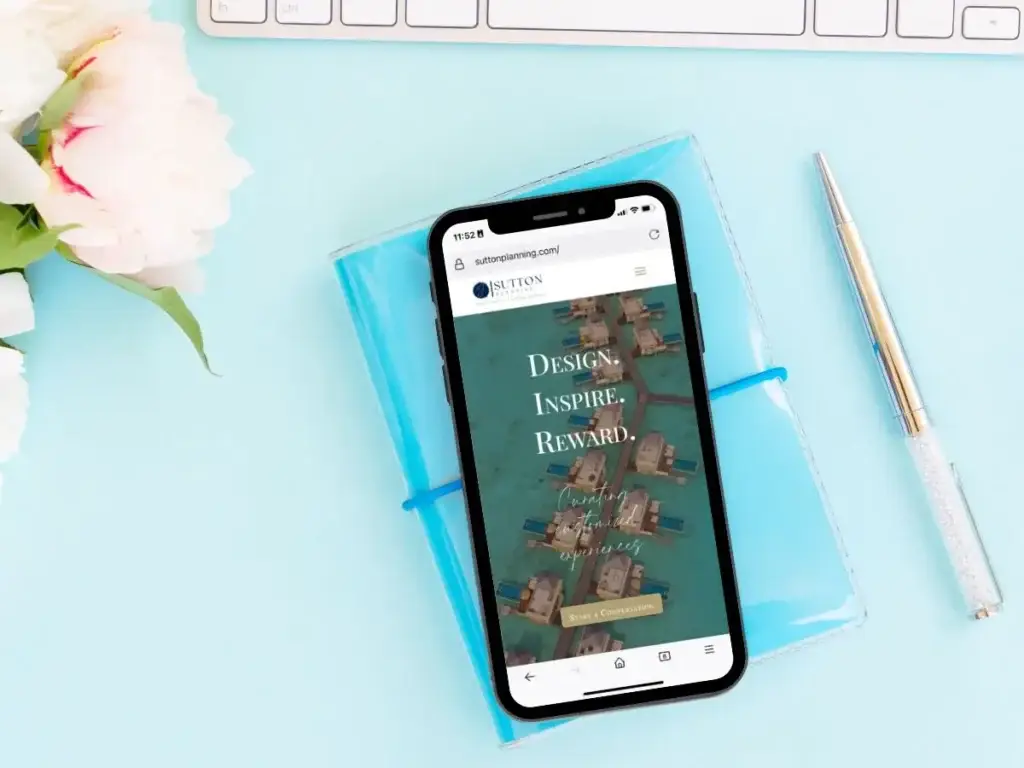 A phone with travel apps on it next to a keyboard and flowers.
