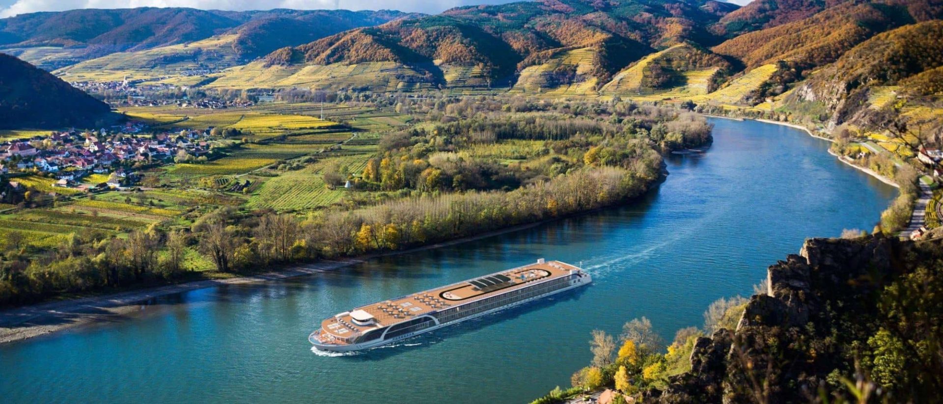 A cruise ship traveling down a river in a valley.