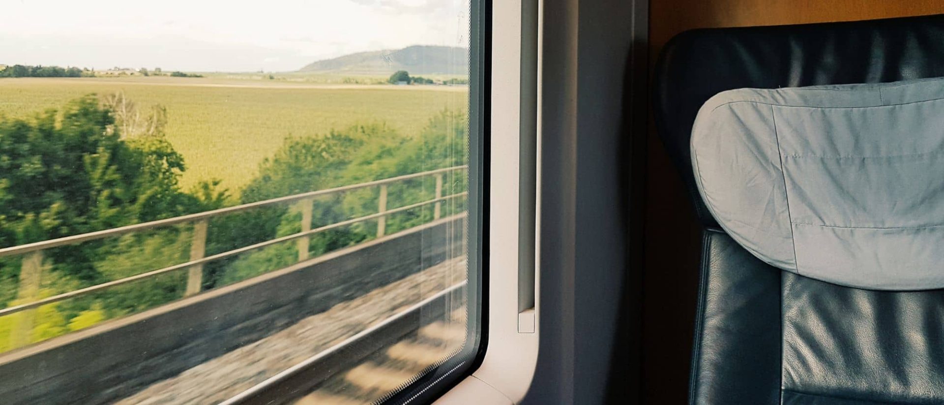 A seat on a train with a view of a field.