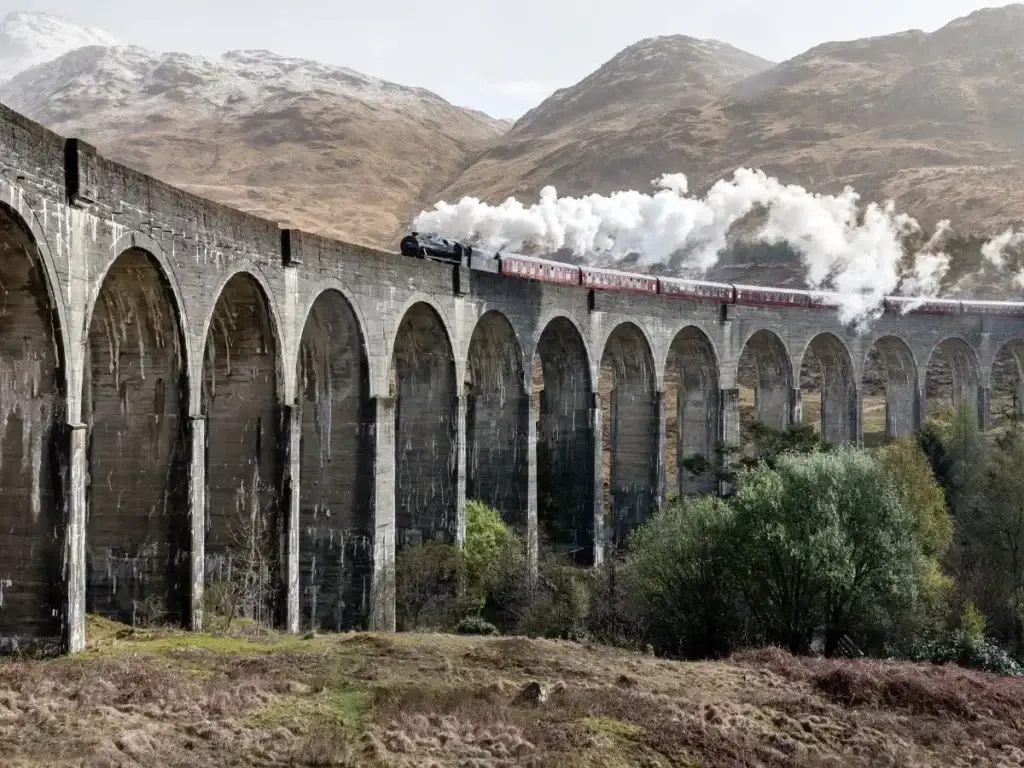 A luxury train traversing a scenic viaduct in Scotland.