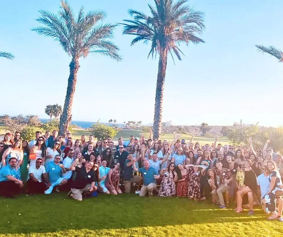 a group of people posing for a picture in front of palm trees.